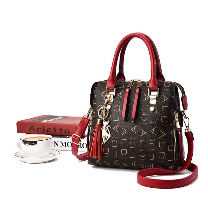 Women's PU leather top-handle handbag with red handles, tassels, crossbody strap, black monogram pattern, gold hardware