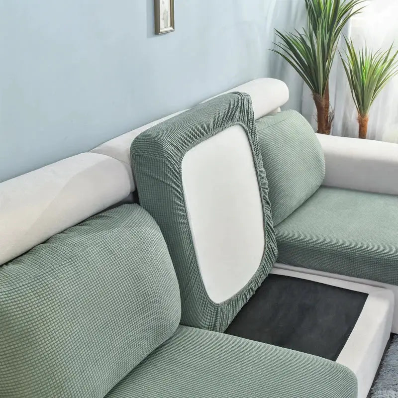 Set of sage green textured sofa seat cushion covers on a light sectional; removable and washable.