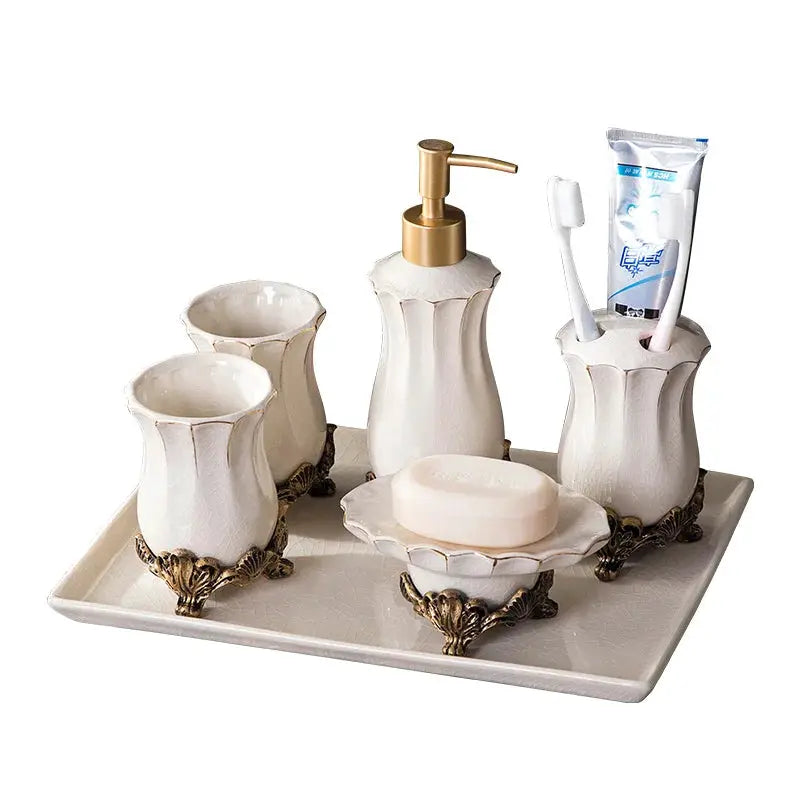 Simples Market white ceramic five-piece bathroom set with gold pump, toothbrush holder, cups, soap dish on ornate tray.