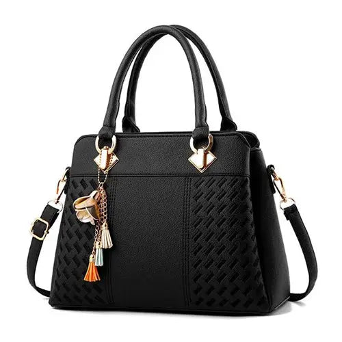 Tote bag by Simples Market in black PU leather with tassel charms, top-handle and crossbody strap.