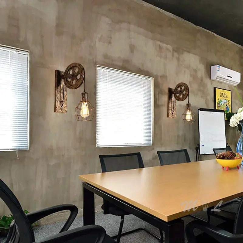Industrial pulley wall sconces with metal cage lamps, two units mounted on a concrete wall in meeting room, LED lighting
