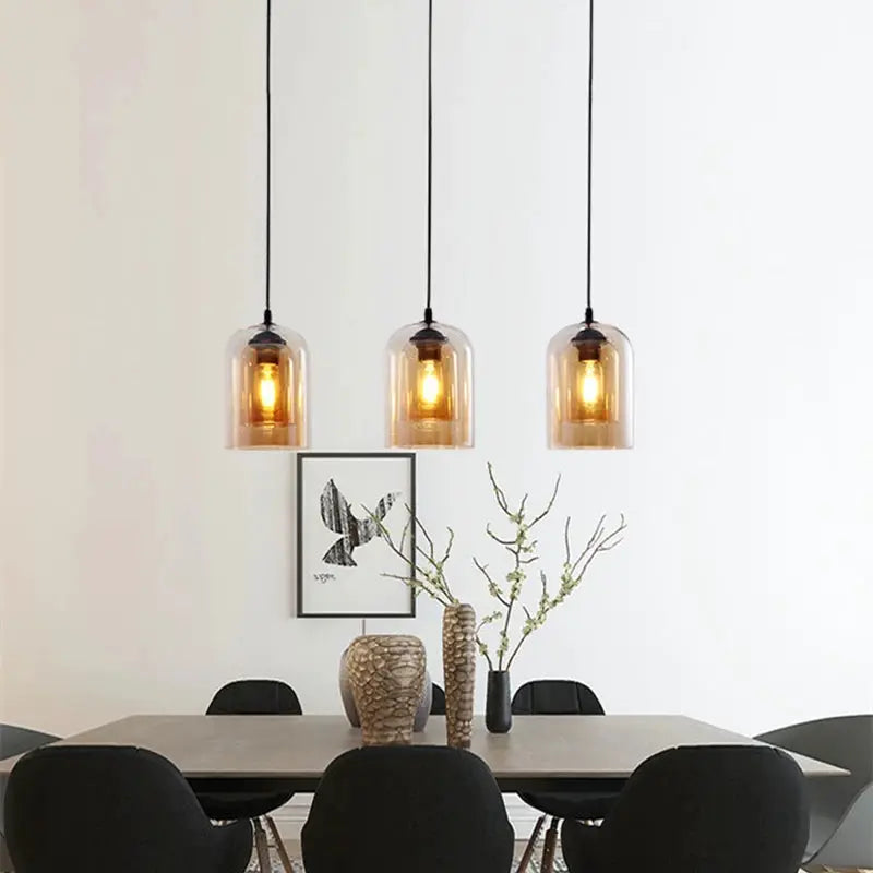 Led pendant lamp trio in amber glass over a modern dining table