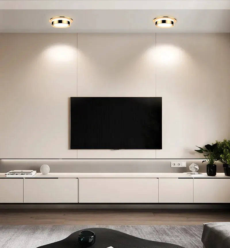 Pair of chrome round recessed LED downlights on ceiling, warm ambient lighting