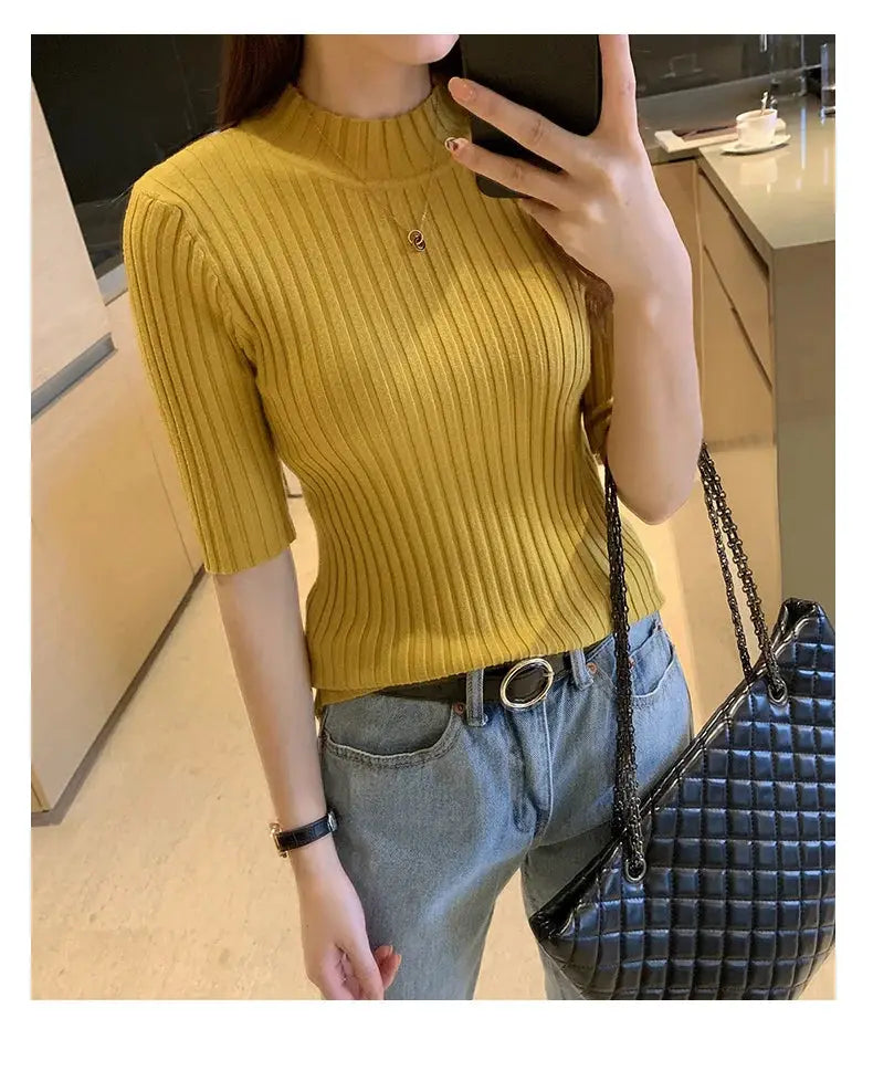 Mustard yellow rib-knit short-sleeve blouse worn with blue jeans and a black quilted chain-strap handbag.