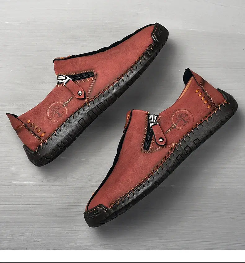 Pair of brown handmade leather men’s slip-on loafers with side zipper and moccasin stitching.