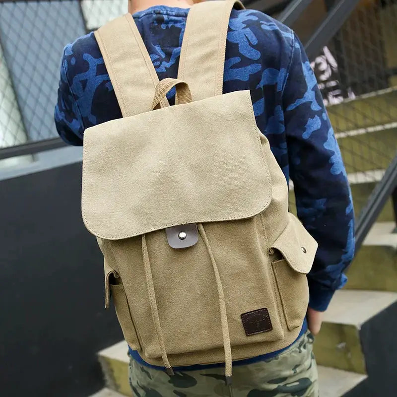 Canvas backpack by Simples Market in beige with flap, drawstring, and side pockets.