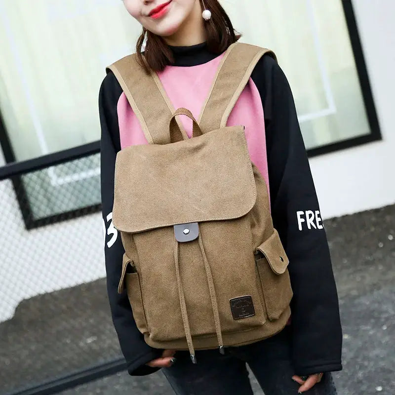 Canvas backpack in tan with front flap, drawstring closure, and side pockets