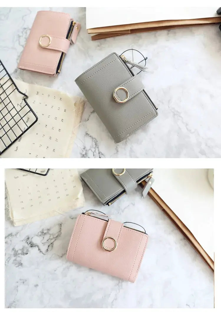 Two short women's wallets in pink and gray PU leather with zip compartments and gold ring closures.