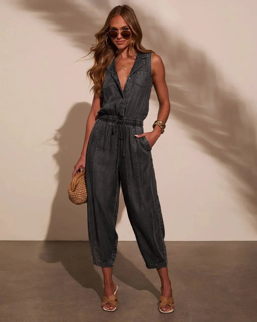 Women’s sleeveless denim jumpsuit with drawstring waist, front pockets, and casual relaxed fit