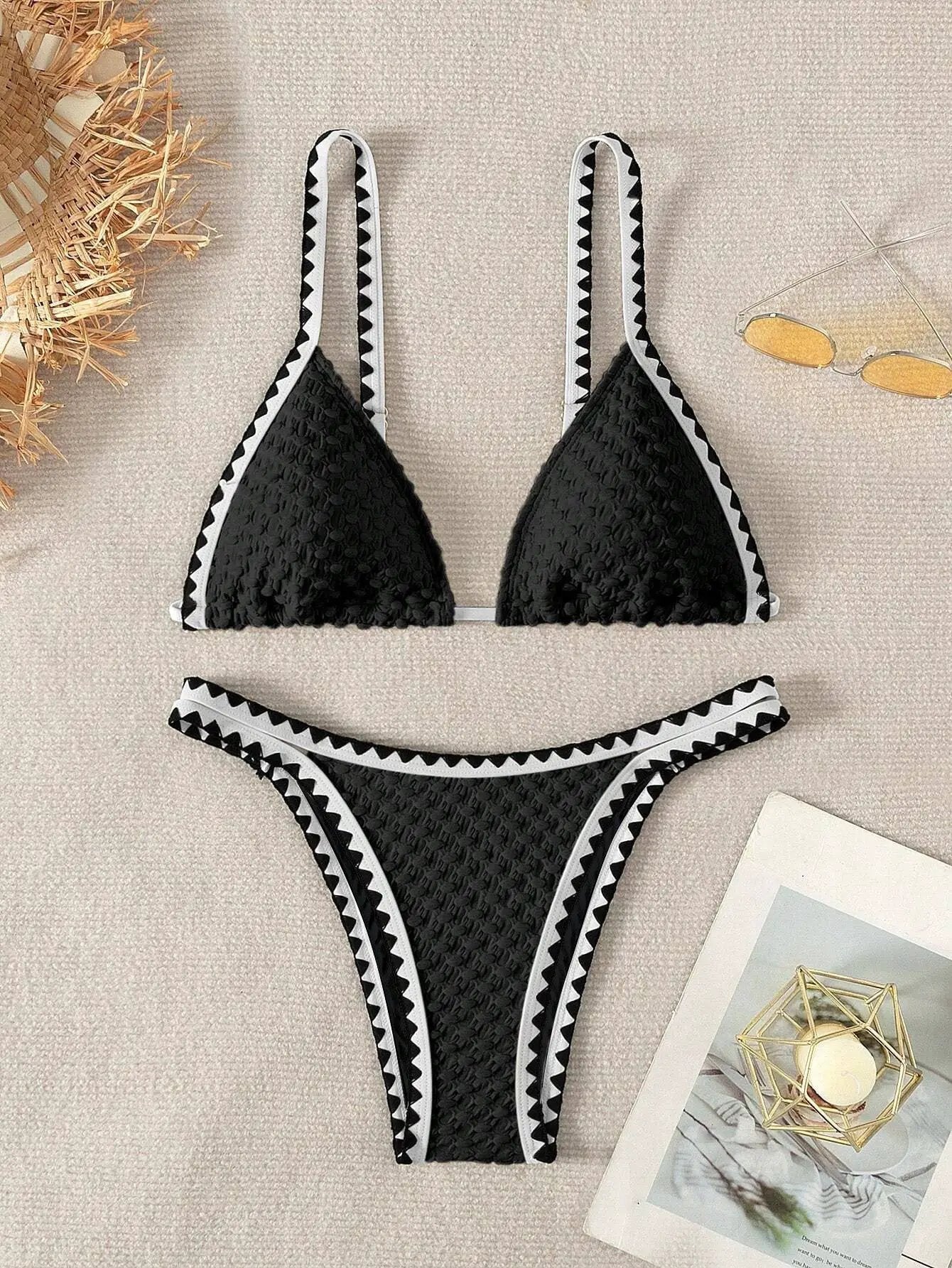 Two-piece black bikini with textured fabric, triangle top and high-cut bottoms, white zigzag trim along edges
