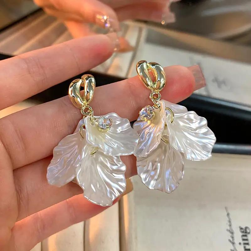 Pair of Simples Market glossy shell flower pendant earrings with gold-tone tops, iridescent petals and crystal accents