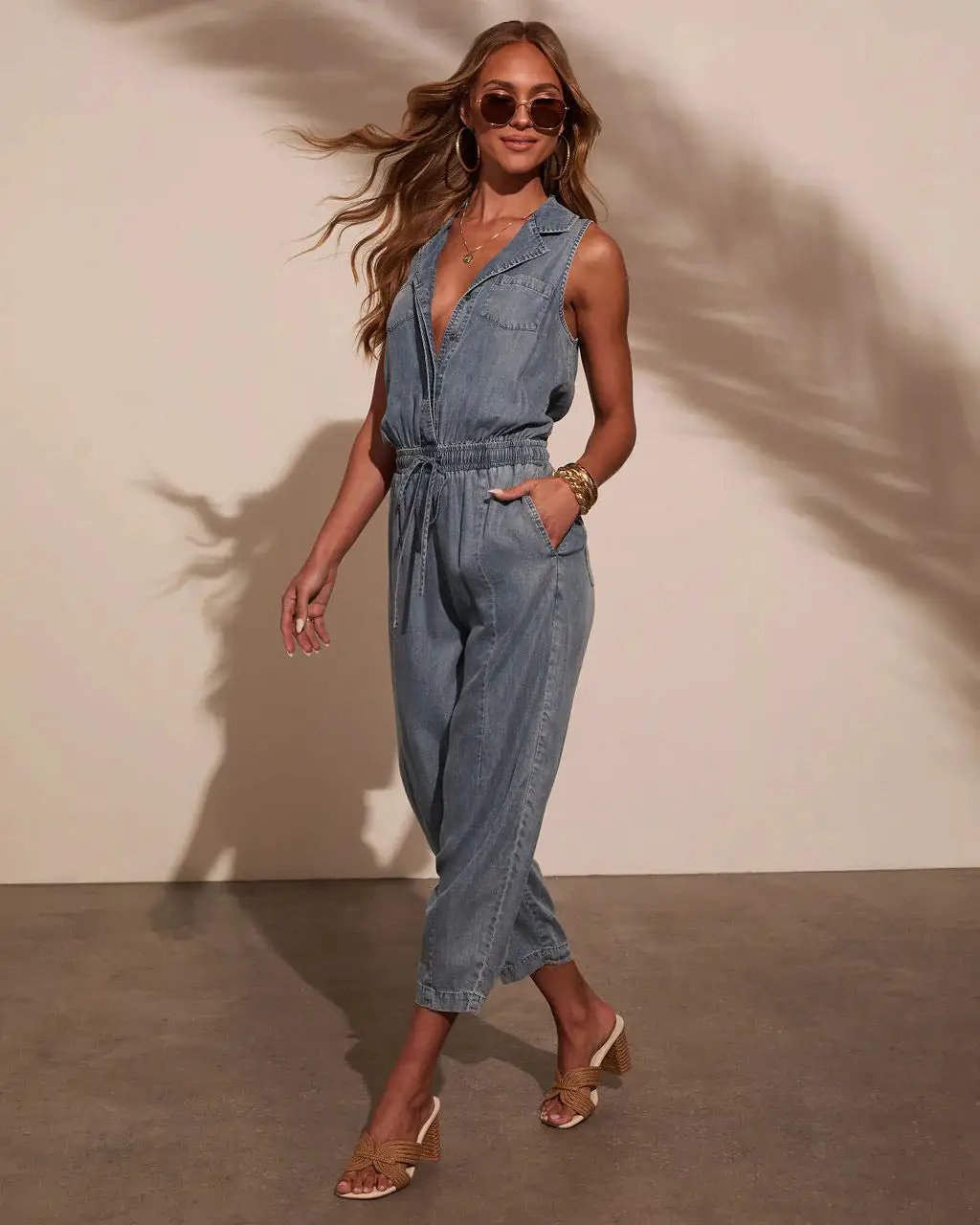 Women’s sleeveless denim jumpsuit romper with drawstring waist and front pockets in light-wash blue casual overalls