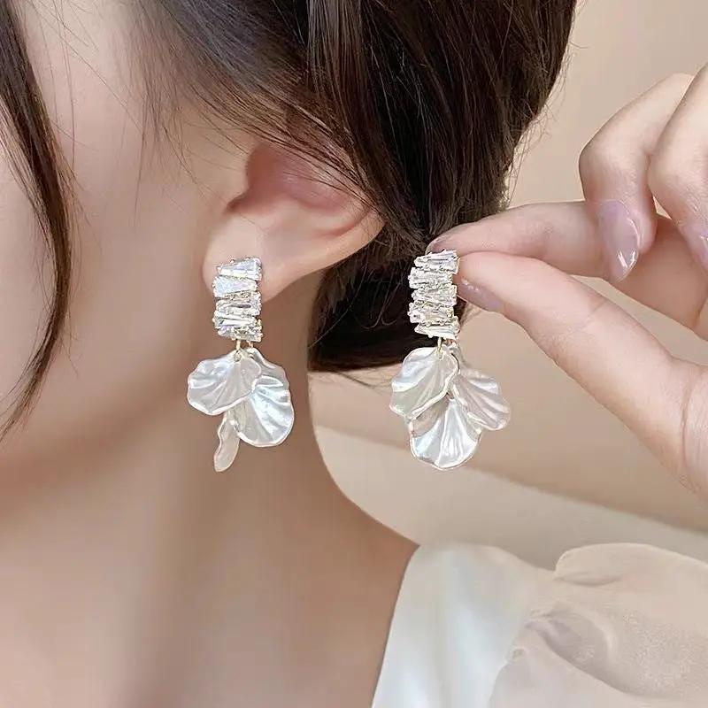 Pair of glossy shell flower pendant earrings with crystal-studded top and white pearl petals