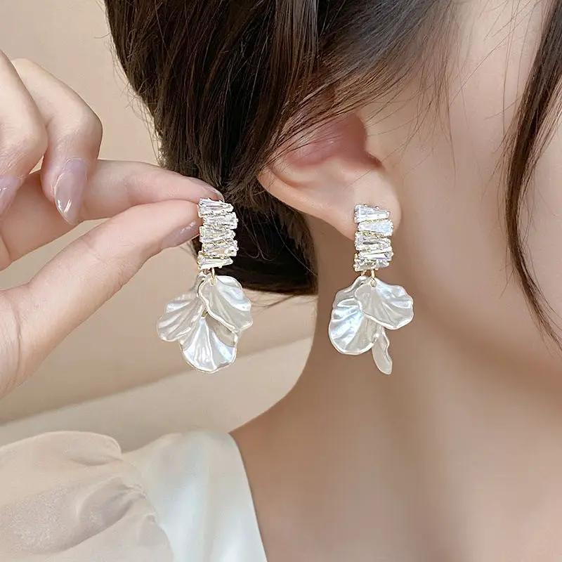 Pair of fashion glossy shell flower pendant earrings with clear crystals and white shell petal drops