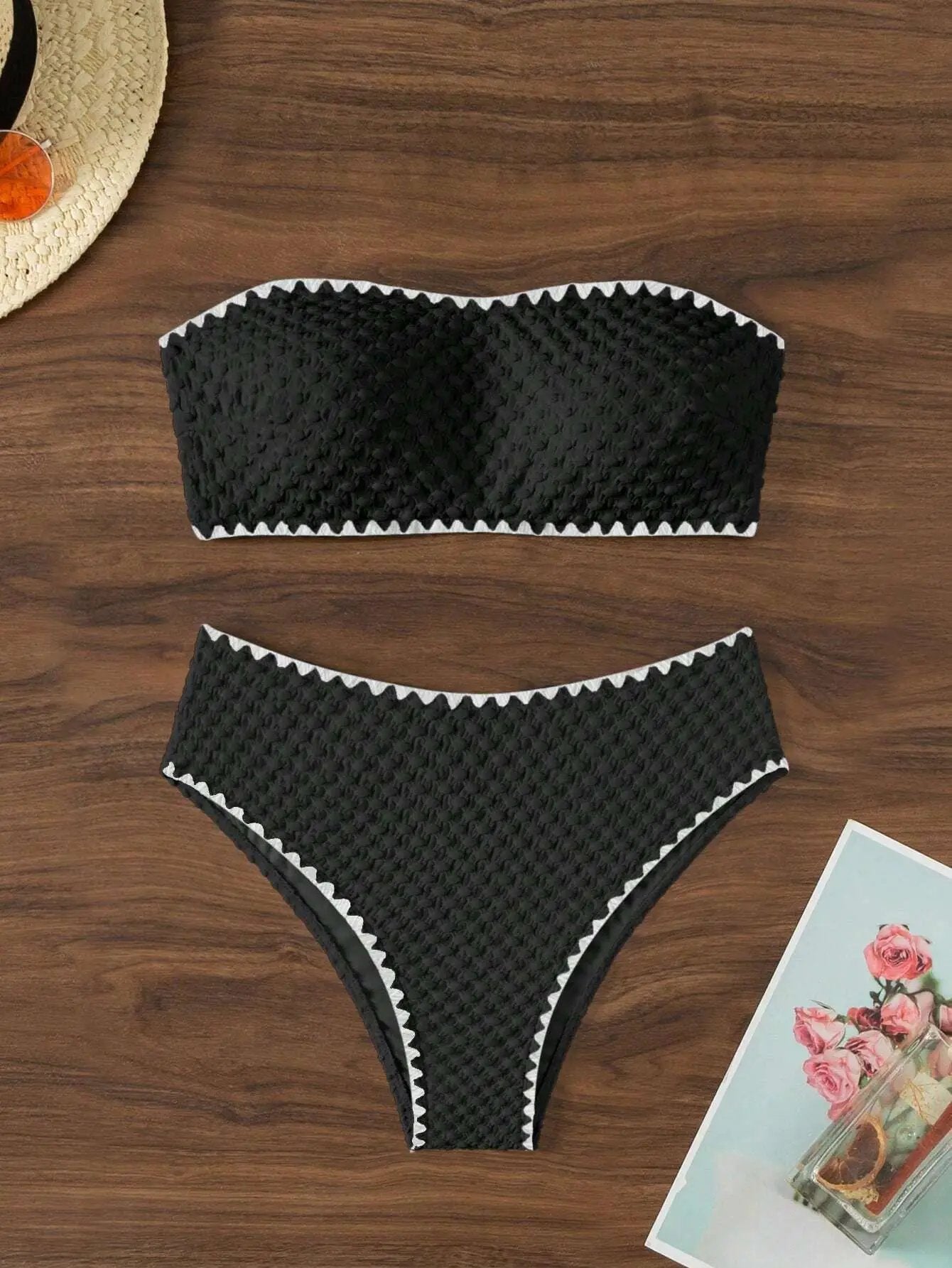 Two-piece black textured bandeau bikini with white zigzag trim; strapless top and high-cut bottom