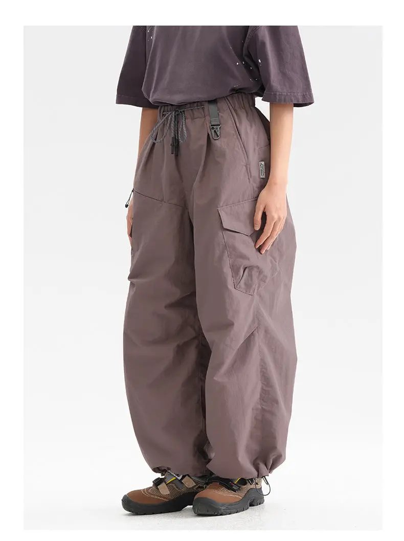 Ultra loose outdoor cargo pants in taupe with drawstring waist, wide legs, and large side cargo pocket.