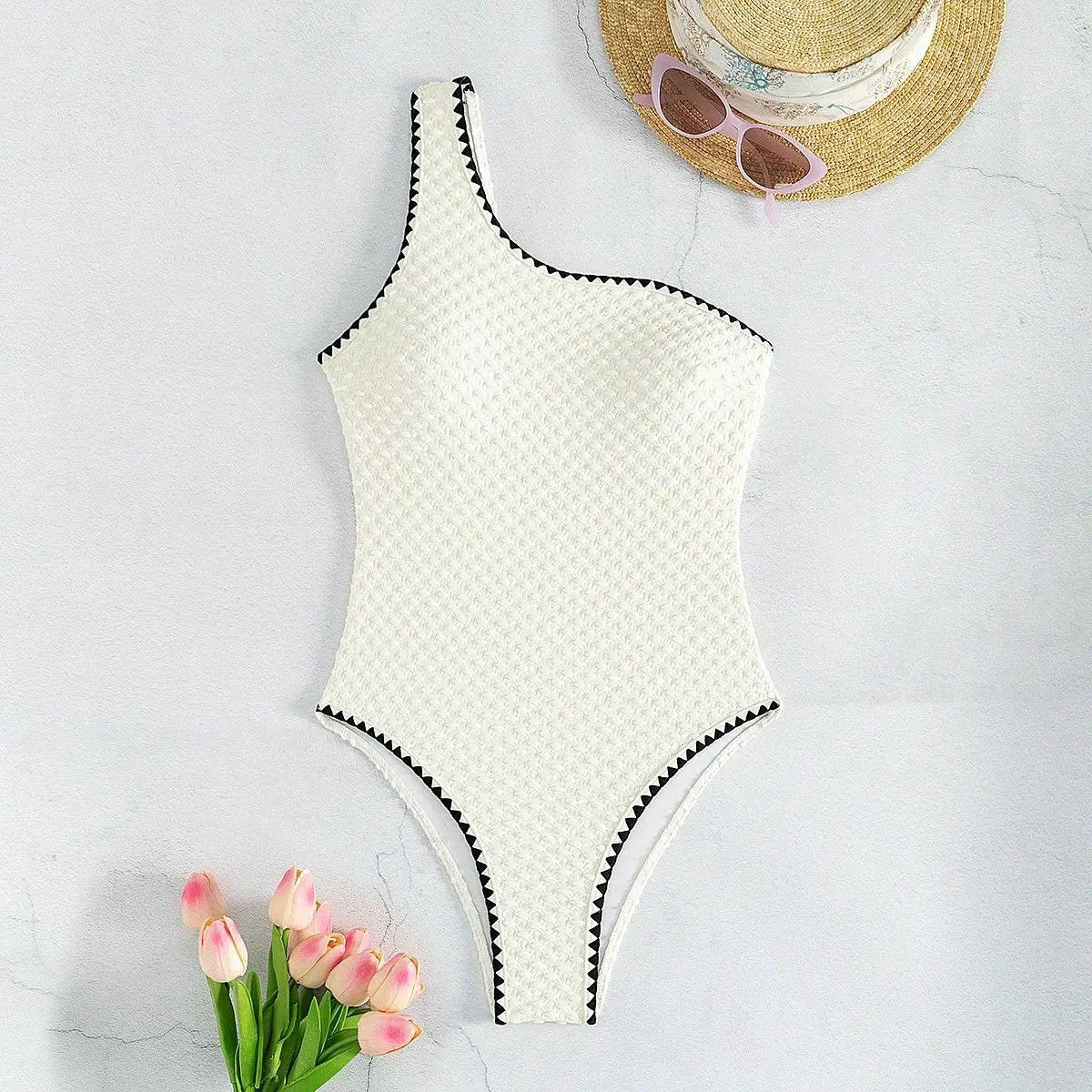 Simples Market white textured one-piece swimsuit with a single shoulder strap and black zigzag trim