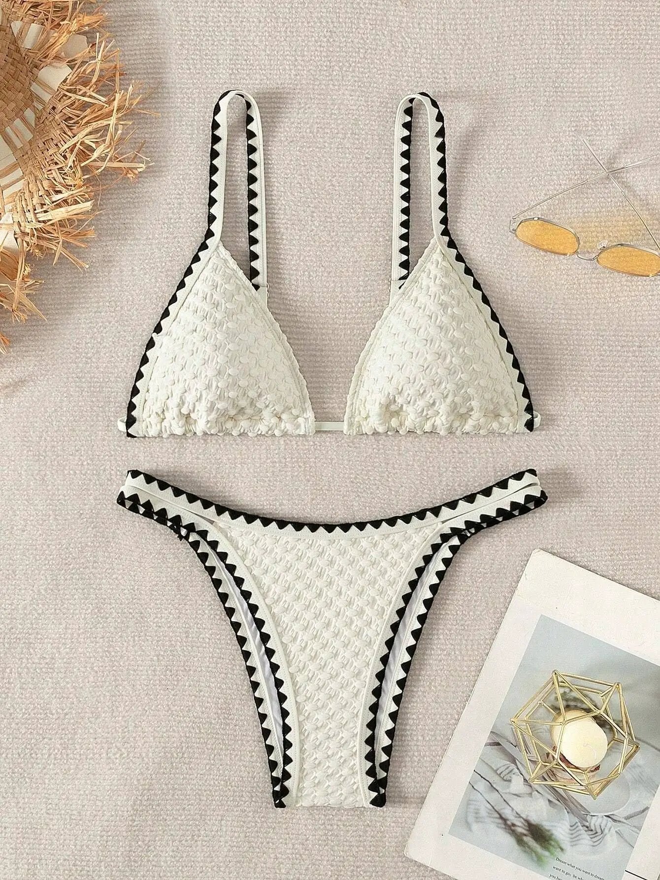 White two-piece bikini set with textured fabric and black zigzag trim; bandeau top and high-cut bottom
