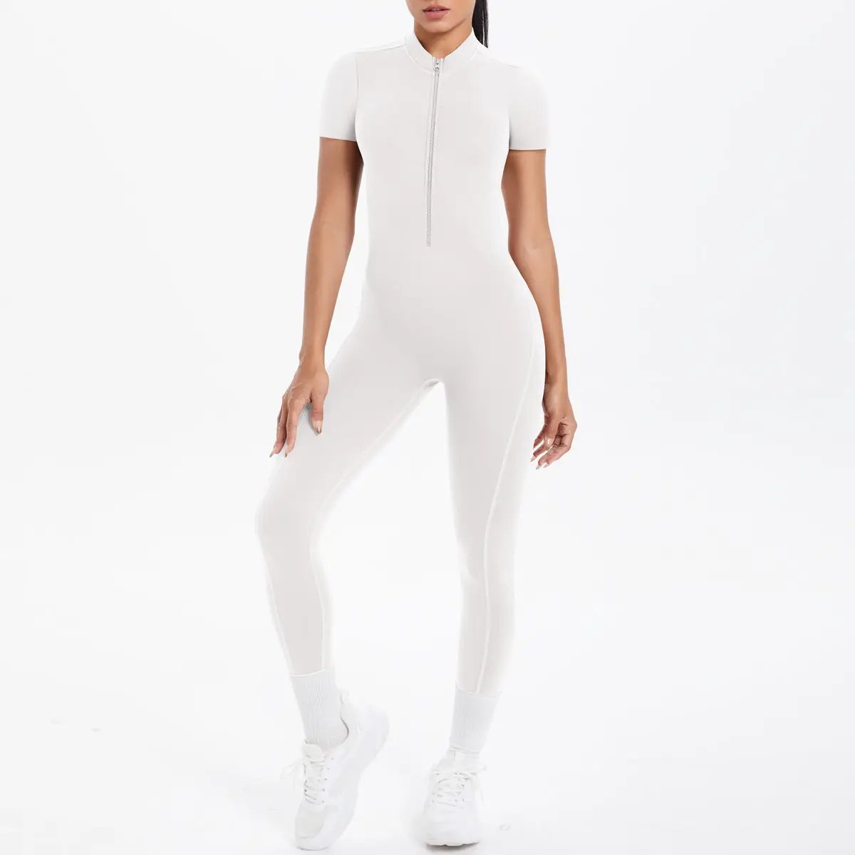 White backless bodycon scrunch jumpsuit by Simples Market with front zipper, short sleeves, model poses in sneakers.