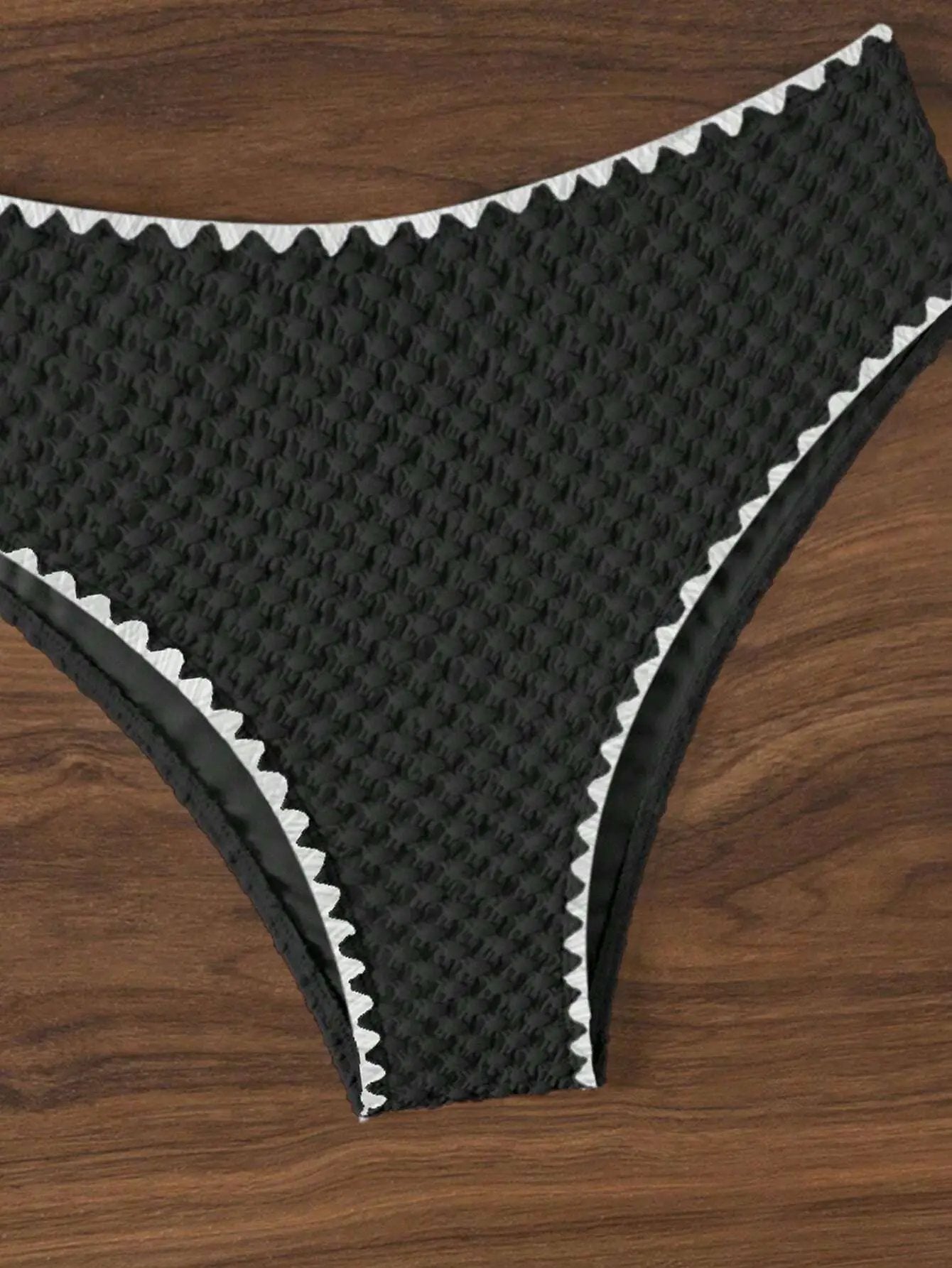 Black textured bikini bottom with white zigzag edging, part of a two-piece swimsuit