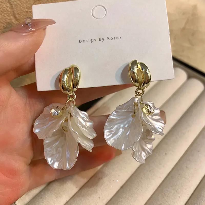 Pair of fashion earrings: gold-tone drop with glossy white shell flower petals and crystal bead accents