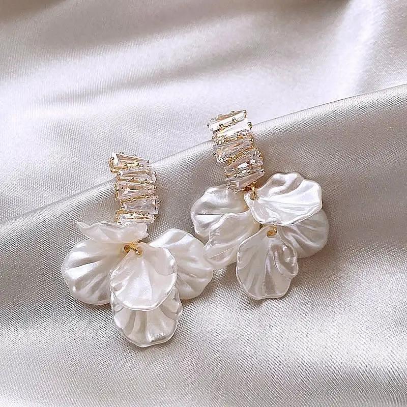 Drop earrings with clear crystal baguette cluster and white shell flower pendants on gold-tone setting