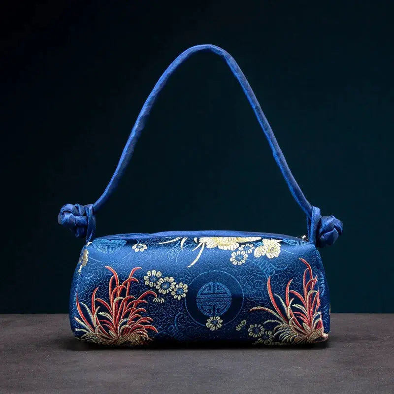 Blue satin shoulder bag with gold floral embroidery and circular emblem by Simples Market