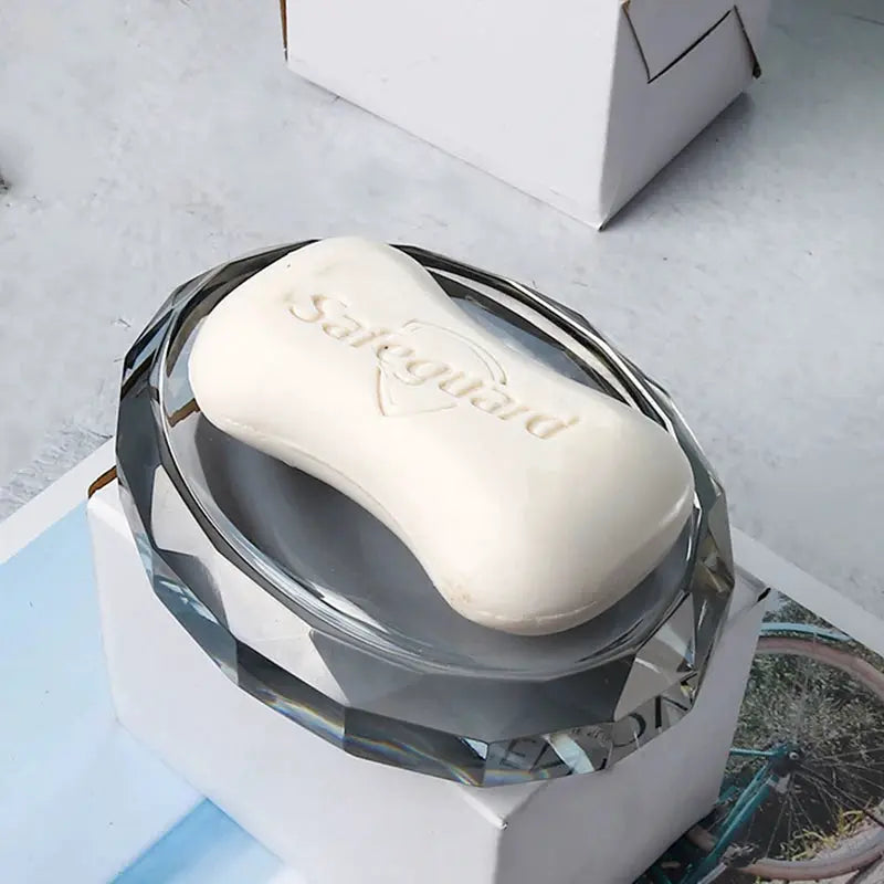 Crystal glass soap dish with a white embossed soap bar on a faceted pedestal.