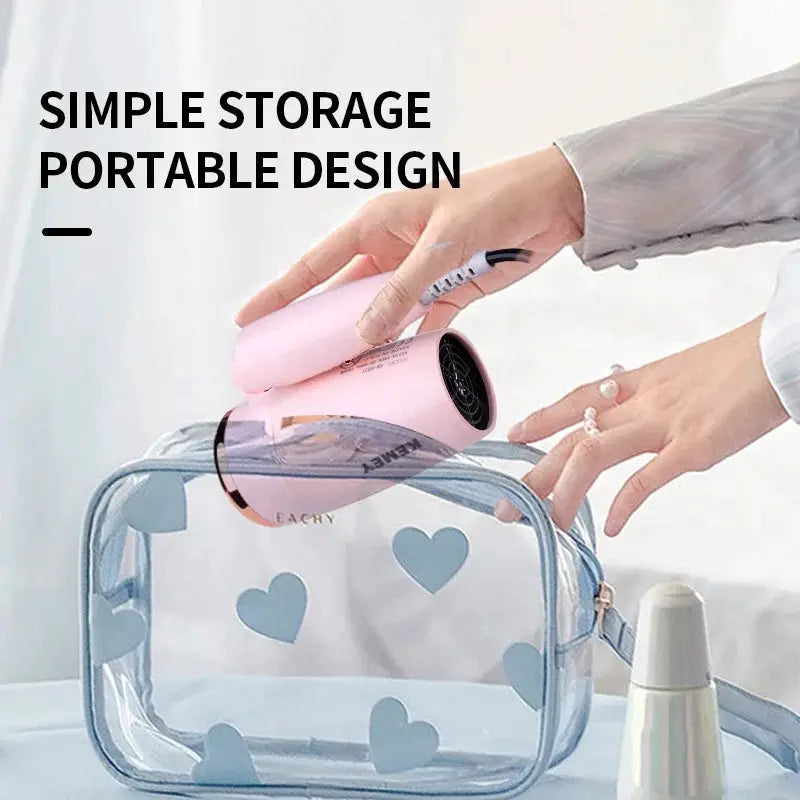 Kemei pink portable hair dryer, compact handheld unit, shown with a clear heart-pattern storage bag