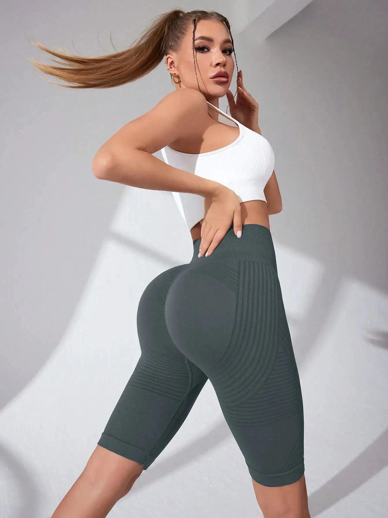 Women's high-waisted seamless yoga shorts in dark green, knee-length with ribbed contour panels