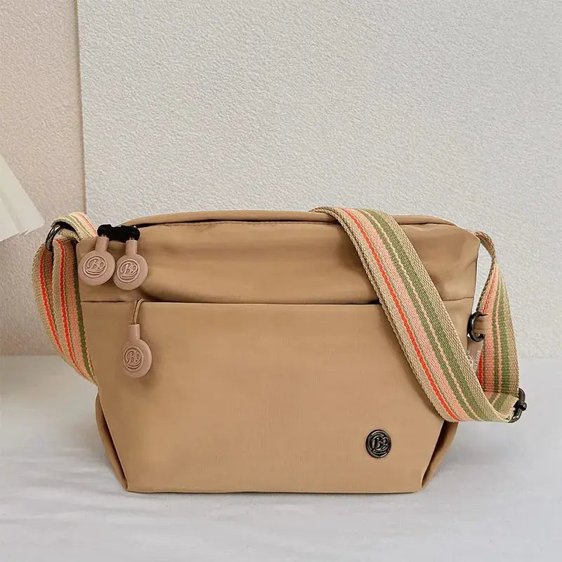 Simples Market beige nylon crossbody bag with adjustable striped strap, zipper closure, small logo plaque