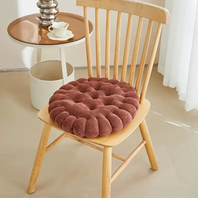 Biscuit-shaped plush cushion seat pad on a wooden chair, burgundy tufted fabric.