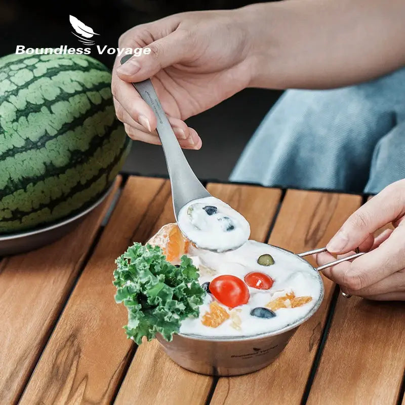 Boundless Voyage titanium spoon used for outdoor camping, shown with a creamy soup bowl on a wooden table.