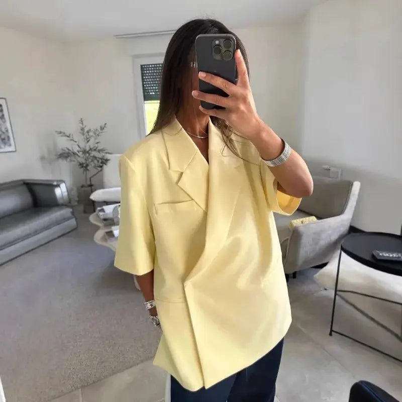 Ladies loose yellow blazer with turn-down collar and short sleeves, paired with high-waist navy shorts.