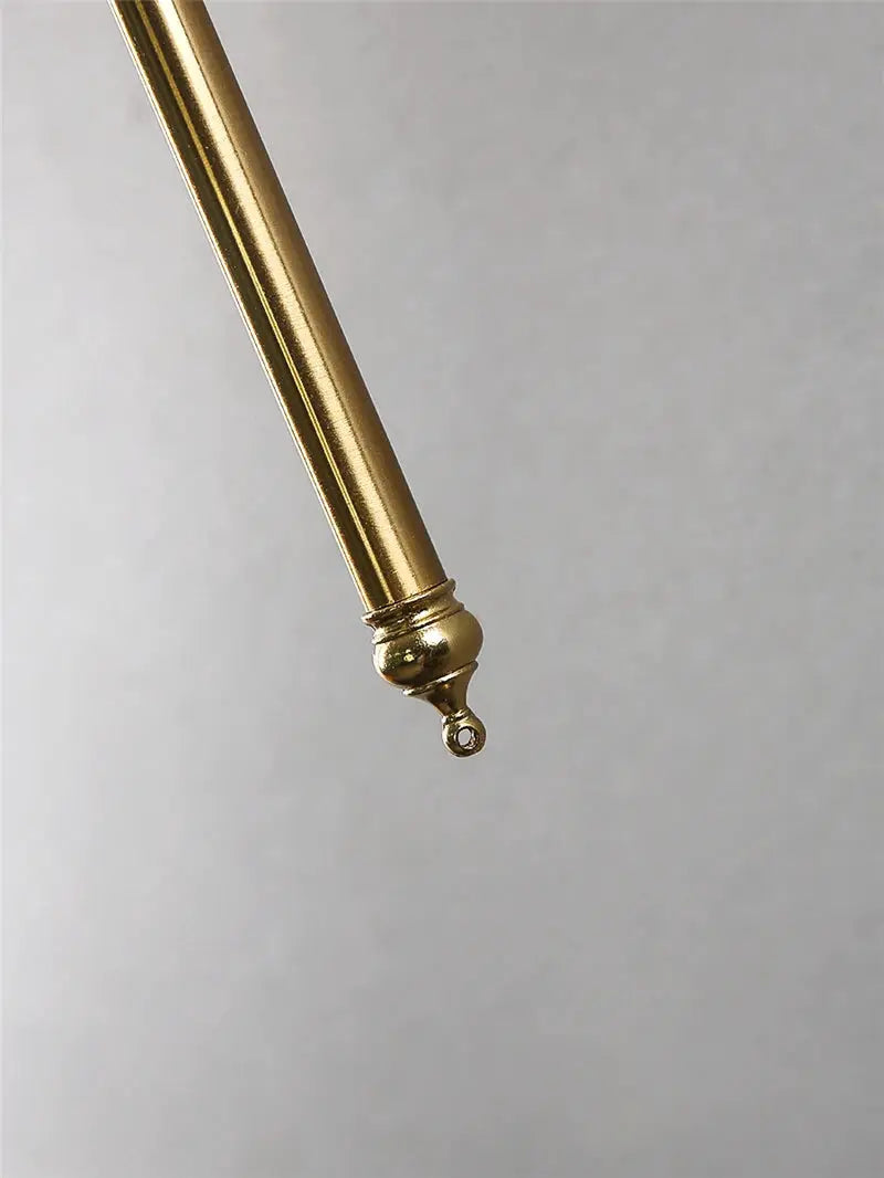 Gold metal wall lamp arm by Simples Market with small loop finial