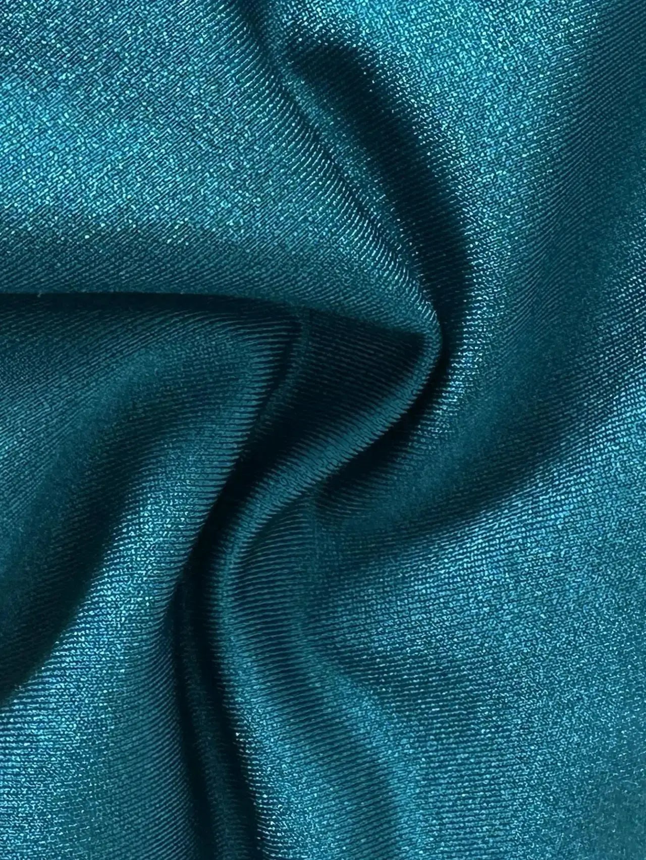 Teal shiny bikini fabric close-up with textured metallic satin folds for swimwear