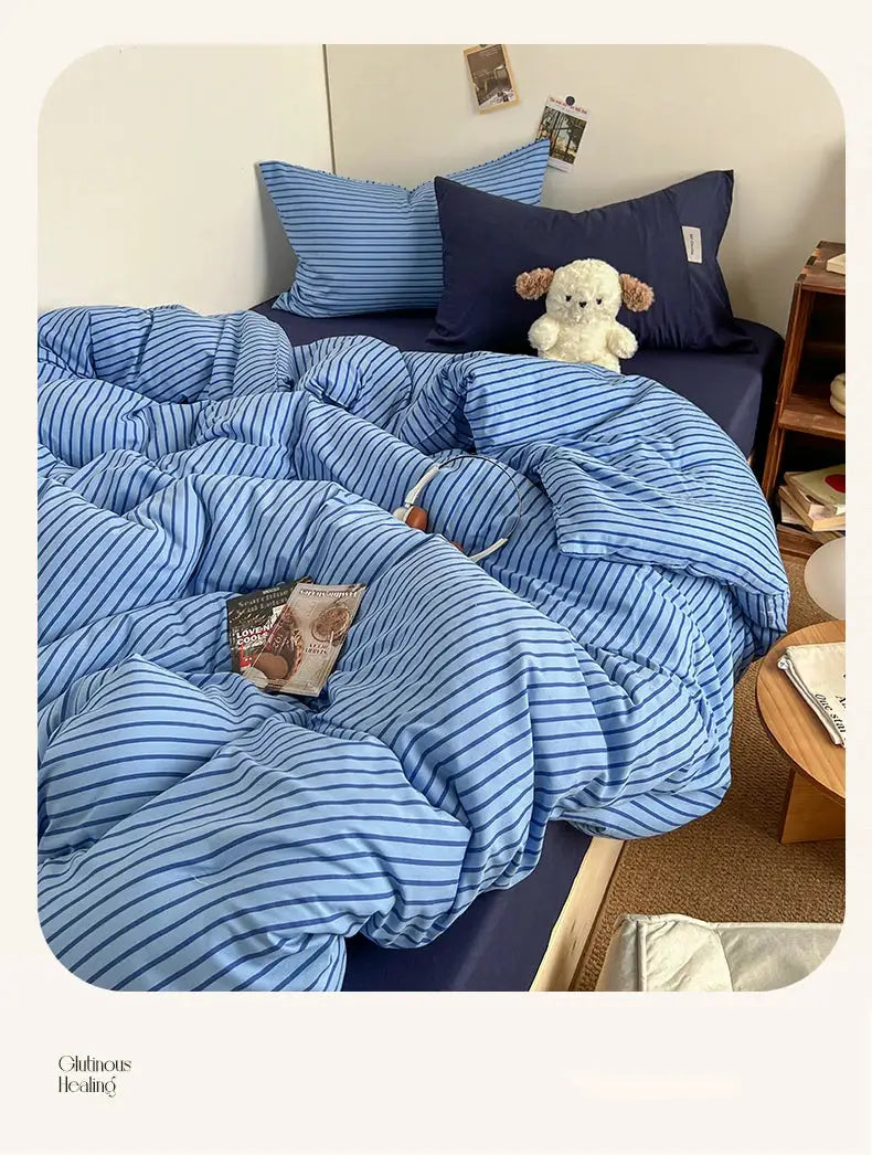 Blue striped bedding set with duvet cover, pillowcases and bedsheet on a bed