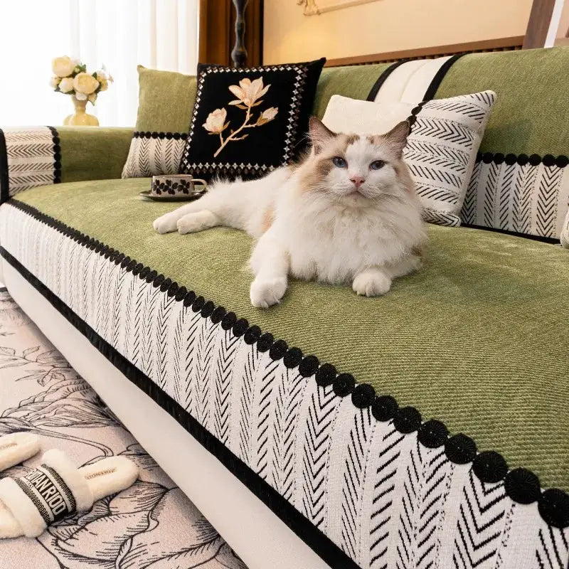 Sofa cover by Simples Market, non-slip contrast-hem twill chenille in green, on a living room sofa with cushions and a cat.