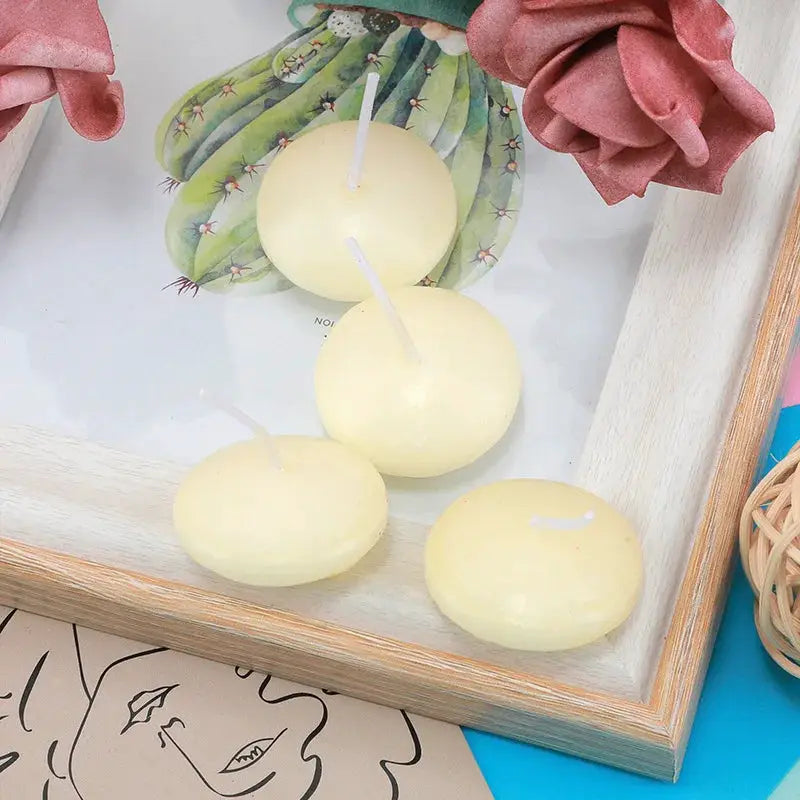 Floating unscented disc candles, set of 4, pale yellow with visible wicks on a wooden tray