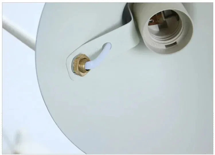 Modern spider-grabbing pendant light by Simples Market; white shade with brass hardware.