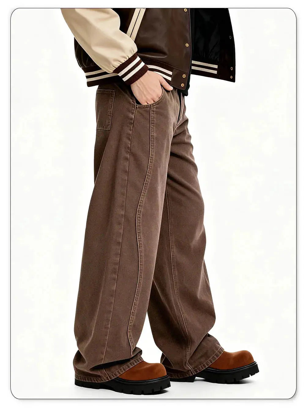 Men's brown baggy wide-leg denim jeans with large front pockets, shown with a beige varsity jacket and leather boots.