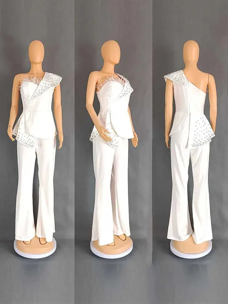 White high-waist strapless jumpsuit with rivet-embellished asymmetric collar and peplum, wide-leg pants.