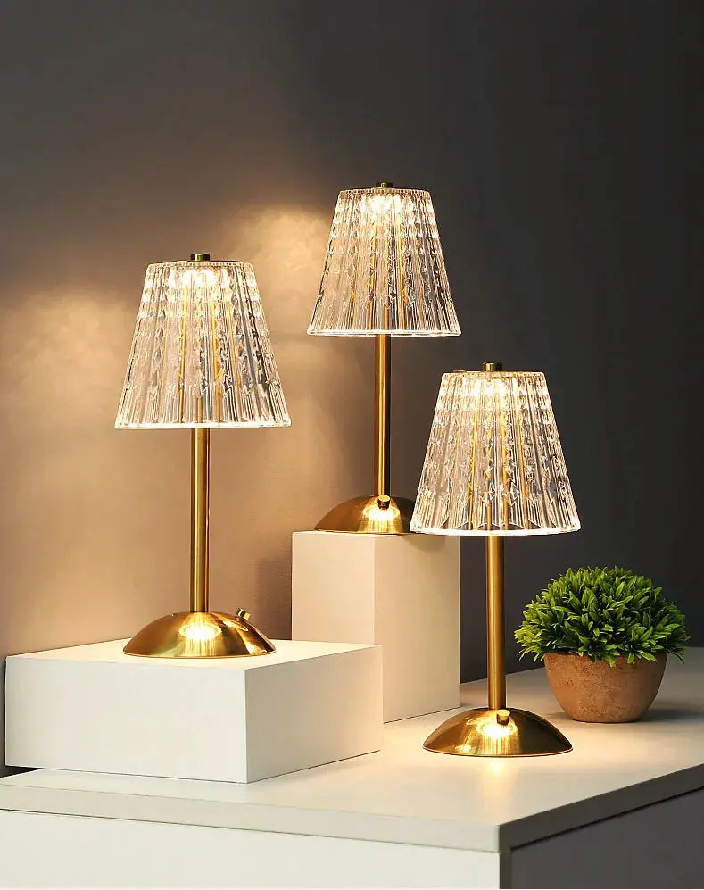 Crystal retro table lamp set: three brass lamps with faceted glass shades on white display blocks