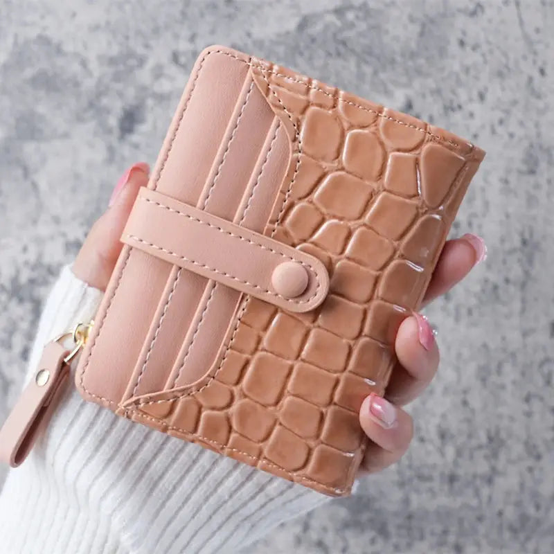 Mini crocodile-print clutch wallet with card slots and snap strap in blush pink