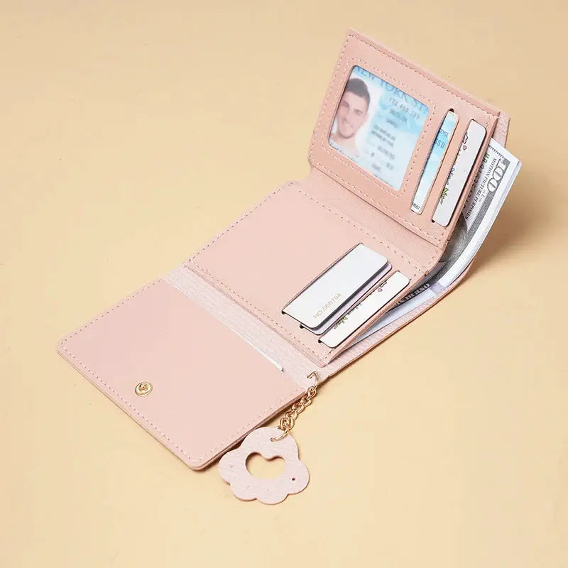 Pink short-style purse wallet with ID window, card slots, and gold-tone flower charm chain