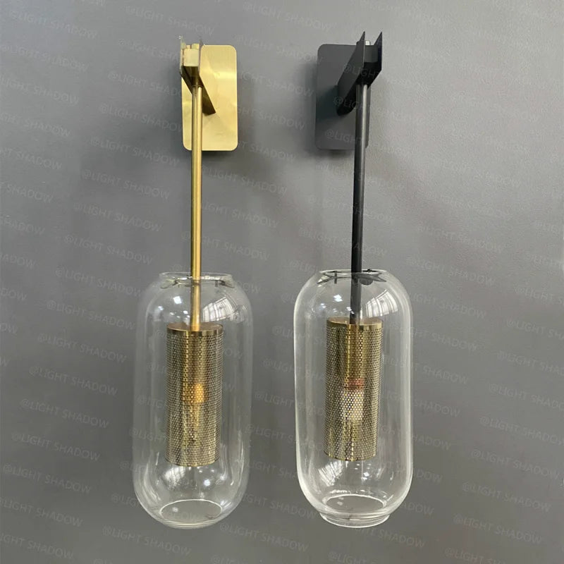 Pair of modern glass wall light sconces with clear glass globes and brass and black metal finishes