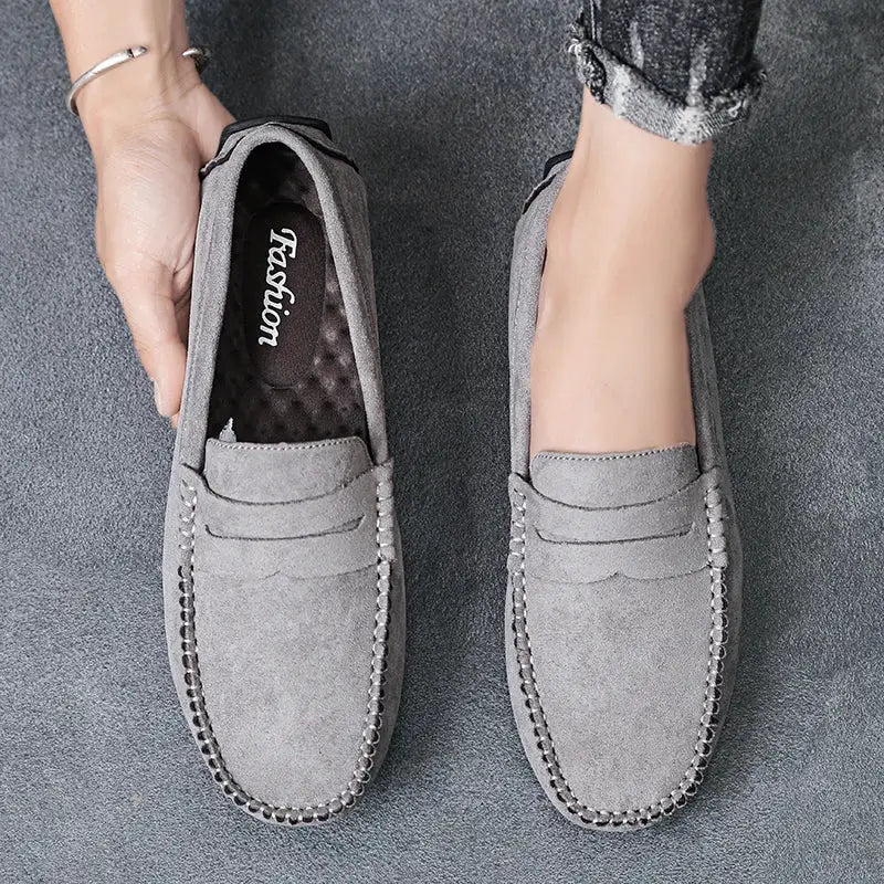 Pair of grey suede men's loafers; slip-on driving shoes with stitched moccasin detailing.