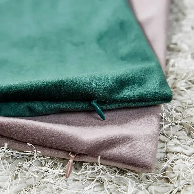Two velvet cushion covers in emerald green and soft pink-beige, 45x45 cm, with exposed zippers for living room decor.