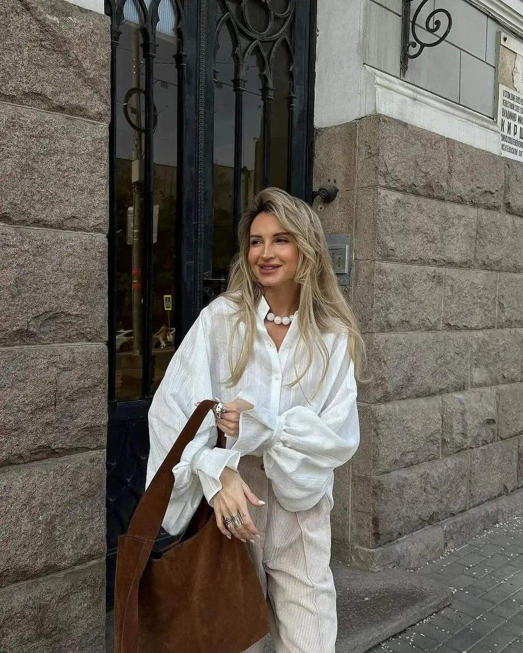 Oversized white women's cotton shirt with long sleeves and a button-front design, paired with a brown tote.