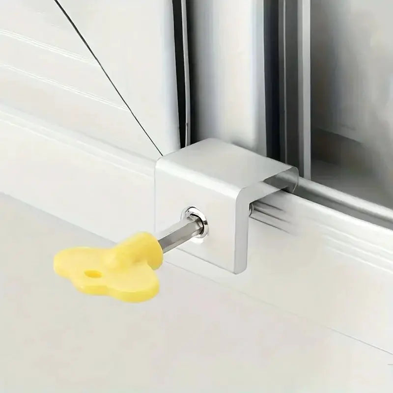 Sliding sash stopper lock with yellow plastic handle mounted on a metal bracket on a white door frame.